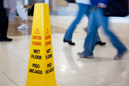 People walking past a wet floor sign