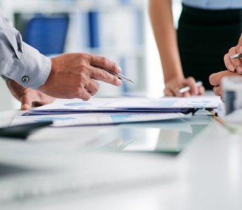 people at table pointing pens